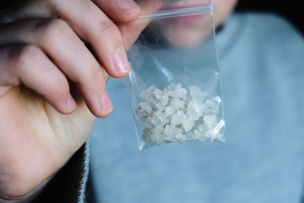 a person holding a bag of drugs showing signs of ice abuse