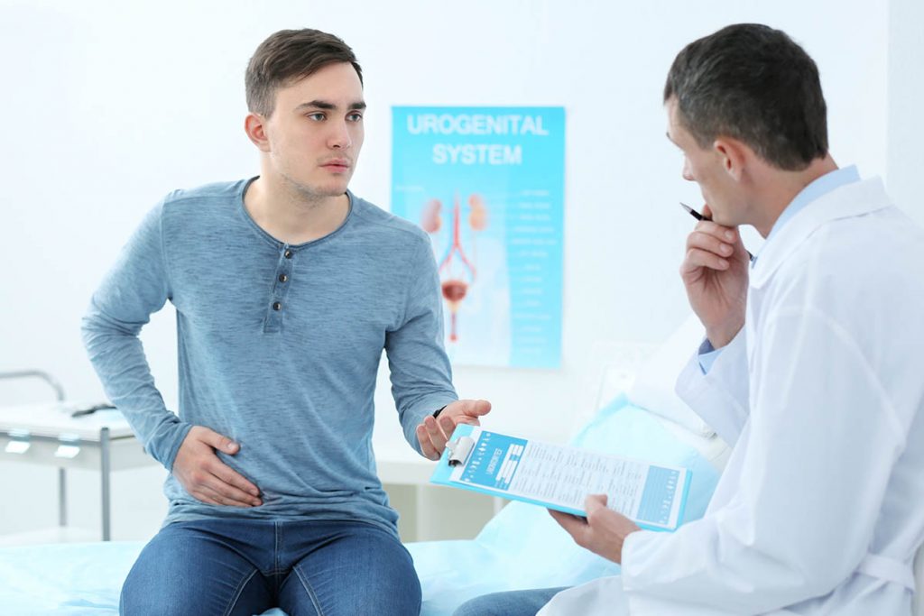 a man holds his side as he discusses the side effects of drug detox and the side effects of alcohol detox with his doctor
