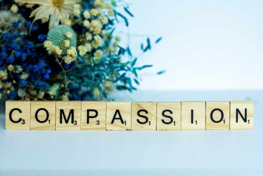 how to practice self compassion spelled out with letters next to flowers